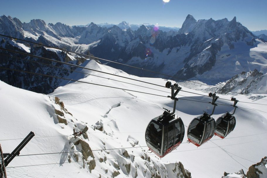 Ski Lift Seilbahnen über schneebedeckte Berge mit klarem Himmel und Sonnenlicht.