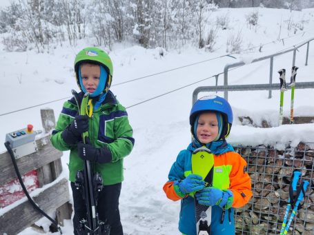 rOSSI cLUB Zwei Kinder in Skibekleidung stehen lächelnd im Schnee.
